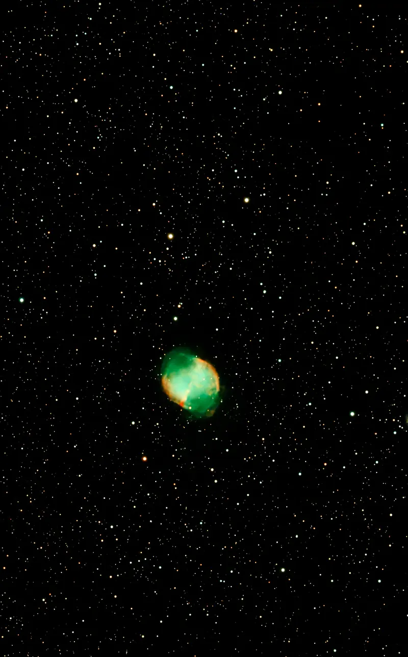 La nebulosa Dumbbell, una mancha verde y rosa entre cientos de estrellas