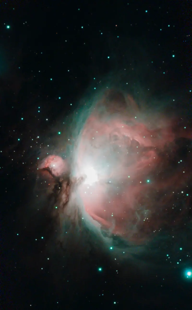 La nebulosa de Orión con nubes de gas rosas y azul verdoso entre estrellas