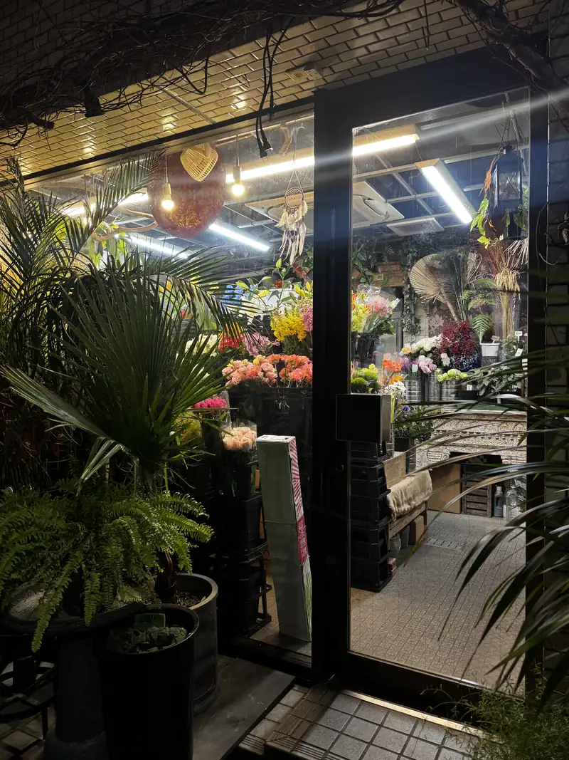 El interior iluminado de una florería de noche, con plantas en la entrada