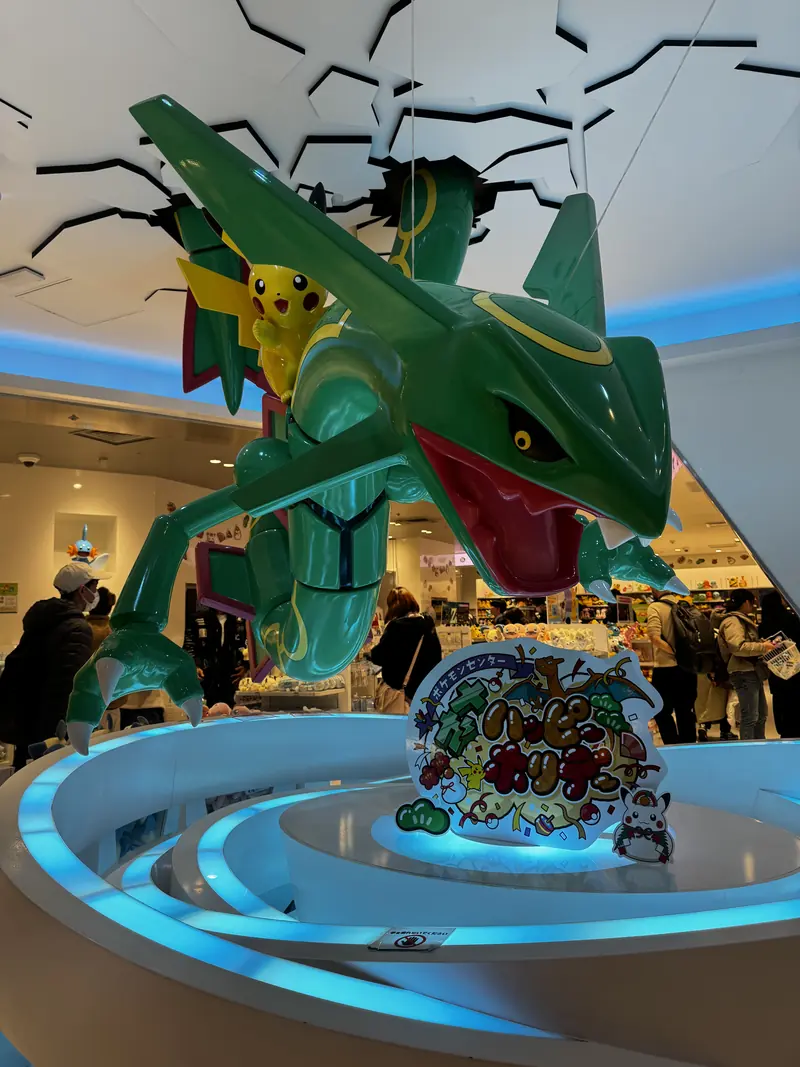 Una figura grande de Rayquaza con Pikachu en una tienda iluminada de azul
