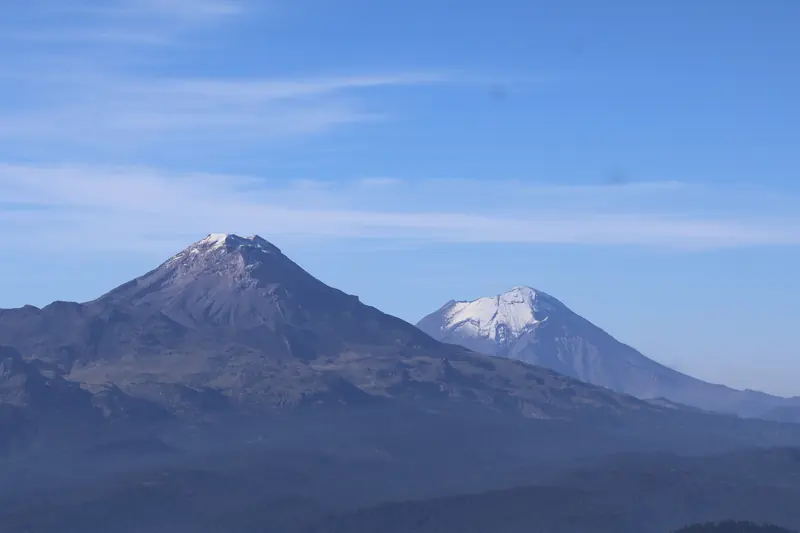 El Popocatépetl y el Iztaccíhuatl vistos a la distancia bajo un cielo azul