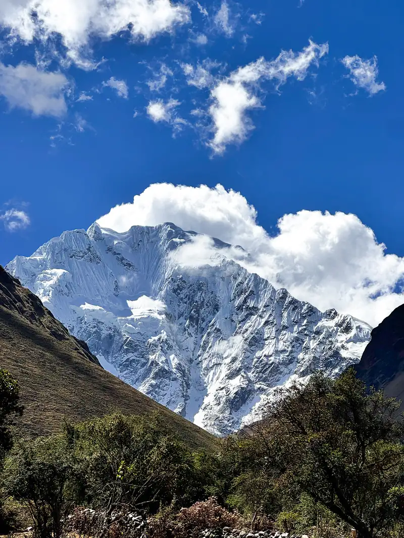 Un pico nevado entre nubes blancas y cielo azul en la cordillera